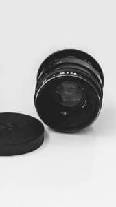 Zwart cameralensobjectief met lensdop op een witte achtergrond
