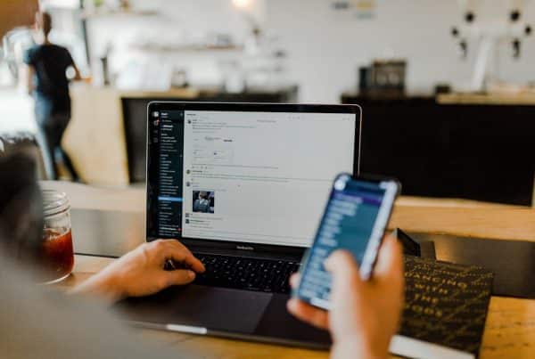 Persoon werkt op een laptop terwijl iemand anders een smartphone vasthoudt in een café