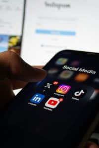Smartphone met map ‘Social Media’ en pictogrammen van X, Instagram, TikTok, LinkedIn en YouTube